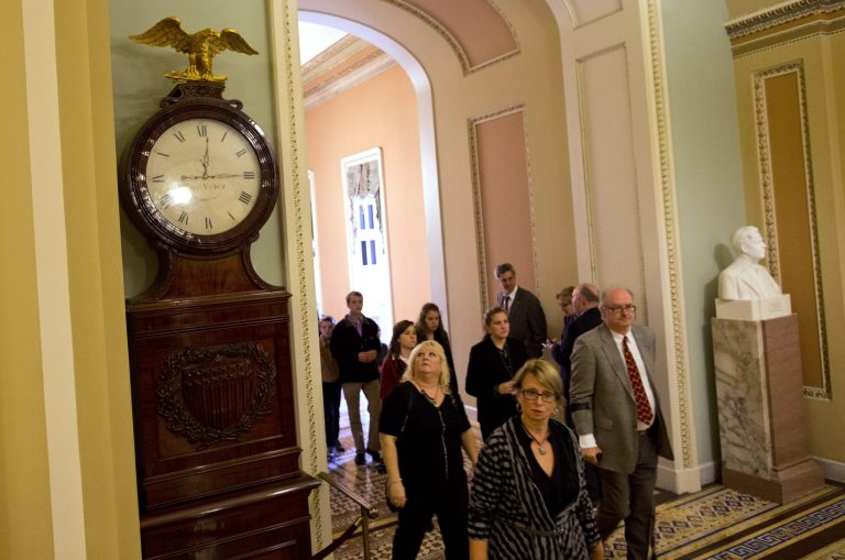 People look toward the Ohio Clock outside the Senate Chamber on Capitol Hill Thursday, Oct. 10, 2013, in Washington.  The Ohio Clock has stood watch over the Senate for 196 years. It stopped running shortly after noon Wednesday. Employees in the Office of the Senate Curator ordinarily wind the clock weekly. But they are among the thousands of federal employees furloughed under the partial shutdown. (AP Photo/ Evan Vucci)