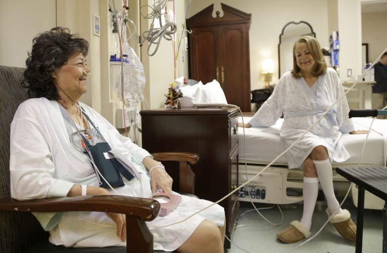 In this Jan. 14, 2014 photo, Irma Myers-Santana, left, and her sister Anna Williamson visit in Williamson's hospital room in Houston. Earlier this month the sisters ended up in the same operating room, each getting one lung from the same donor. (AP Photo/Pat Sullivan)