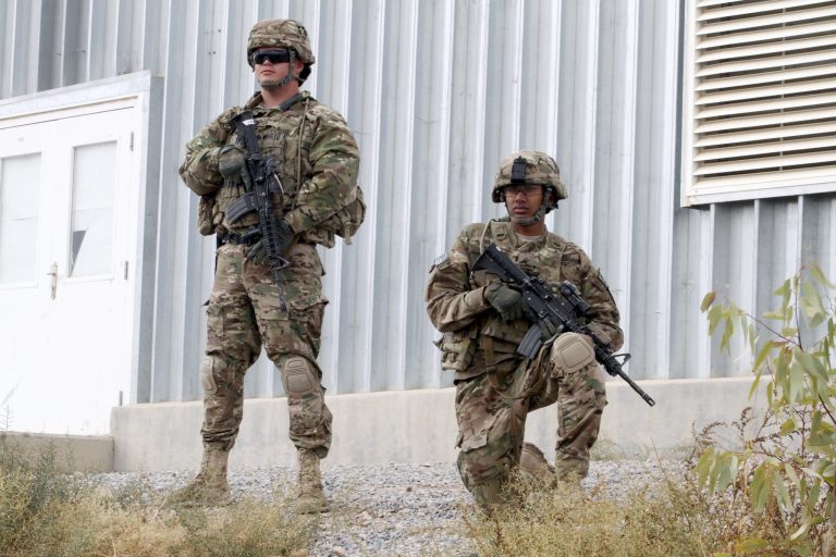   FILE - In this Nov. 28, 2012 file photo, U.S. soldiers with stand guard as they watch the transfer ceremony of security responsibilities from NATO troops to Afghan security forces in Qalat, Zabul province south of Kabul, Afghanistan. The debate over how many U.S. troops will remain in Afghanistan after 2014 comes down to risk. Leaving too few troops in place could stall progress for Afghan security forces. But keeping too many troops there might prolong Afghanistanâs dependence on the U.S. military and NATO. (AP Photo/Allauddin Khan, File)  