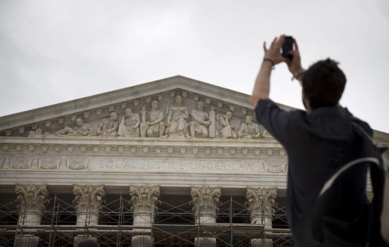 Chris Sharp of Brooklyn, N.Y., takes a photo of the Supreme Court in Washington, Monday, Oct. 7, 2013, as he waits in line for the beginning of the 2013-2014 opening term. The justices take the bench Monday for the start of their new term with important cases about campaign contributions, housing discrimination and government-sanctioned prayer already on tap. Abortion, contraceptive coverage under the president's new health care law and mobile phone privacy also may find their way onto the court's calendar. (AP Photo/ Evan Vucci)