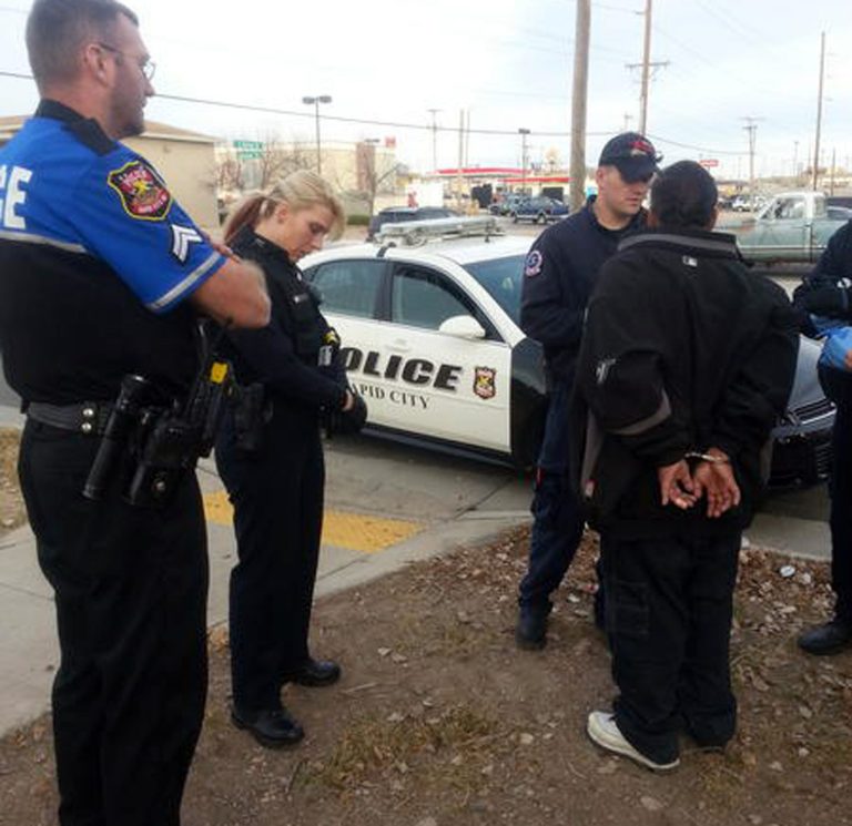   In this Nov. 21, 2012 photo provided by The Rapid City Police Department Officer Ron Terviel, left, and Officer Carmen Visian wait while paramedics check a hit-and-run suspect during a Tweetalong in Rapid City, S.D. On a virtual ridealongs on Twitter, or Tweetalongs, officers post regular updates to Twitter about what they are seeing as they perform their normal on-duty routine. The tweets, which also include photos and links to videos of the officers, can encompass an array of activities. (AP Photo/Rapid City Police, Tarah Heupel)  