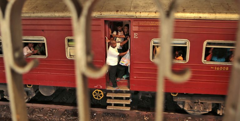 People ride a train that is about to reach Fort railway station in Colombo, Sri Lanka, Saturday, Oct. 11, 2014. The 
