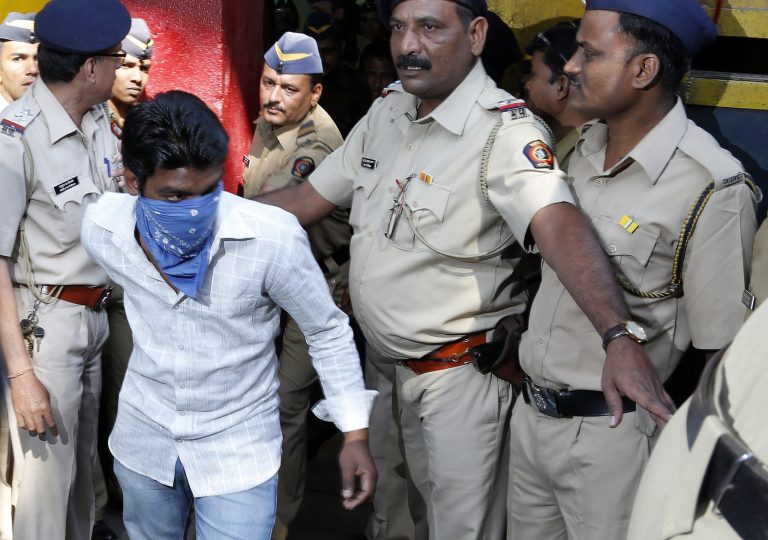 Police officers escort one of the four convicts outside a prison to be taken to a court in Mumbai, India, Friday, March 21, 2014. An Indian court sentenced four men to life in prison on Friday for raping a call-center operator last year inside an abandoned textile mill in the financial hub of Mumbai. (AP Photo/Rajanish Kakade)