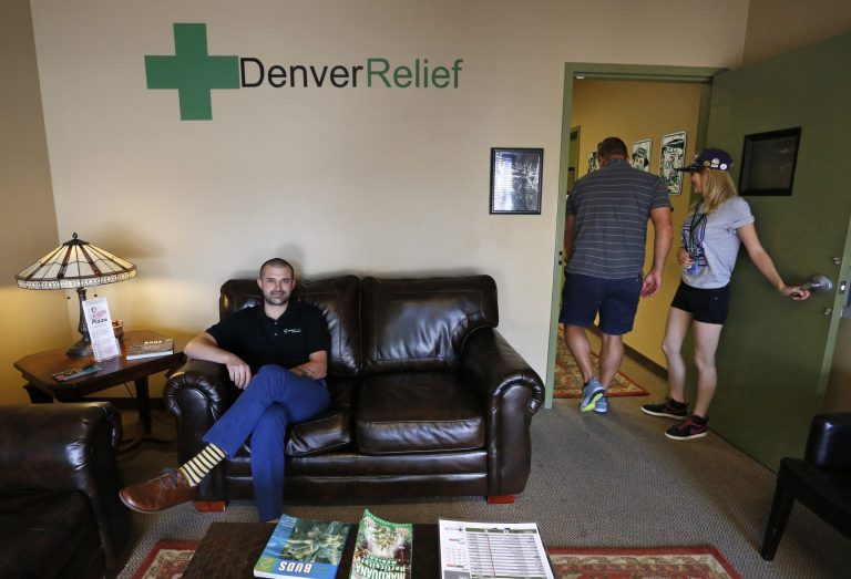 In this Aug. 25, 2014 photo, Kayvan Khalatbari, left, sits on the couch in the lobby of his medical and recreational marijuana store Denver Relief, as his employee Allison Woods escorts a customer into the shop, in Denver. Khalatbari also runs Denver Relief Consulting, which assists current and would-be marijuana-related businesses around the country, as well as owning a chain of pizza restaurants in Denver. (AP Photo/Brennan Linsley)
