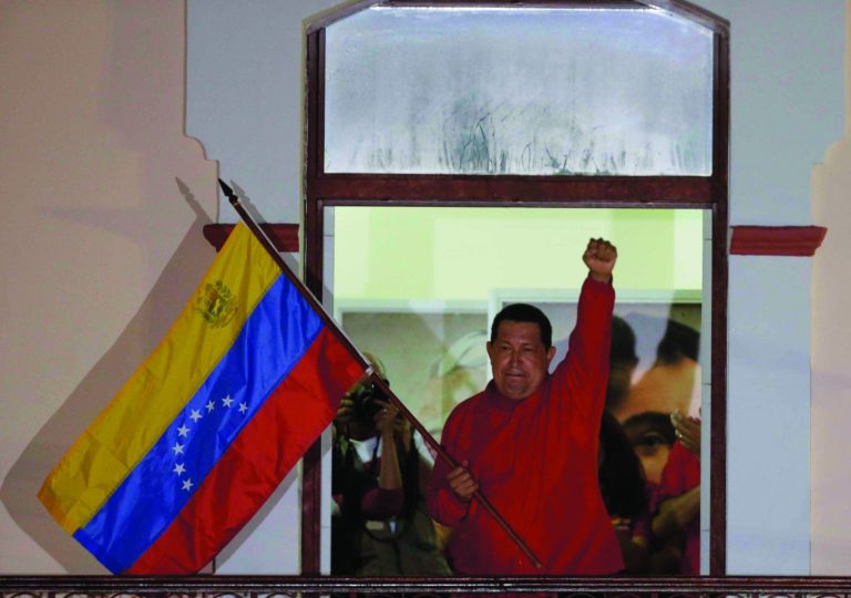 Venezuela's President Hugo Chavez waves a Venezuelan flag as he greets supporters at the Miraflores presidential palace balcony in Caracas, Venezuela, Sunday, Oct. 7, 2012. Chavez won re-election and a new endorsement of his socialist project Sunday, surviving his closest race yet after a bitter campaign against opposition candidate Henrique Capriles.(AP Photo/Fernando Llano)