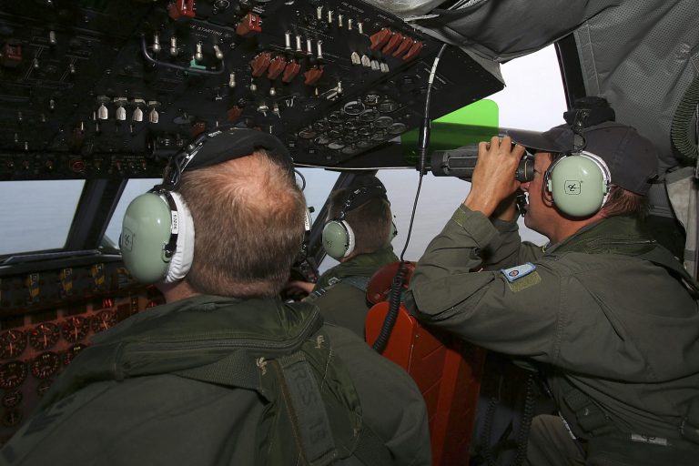 In this Wednesday, March 26, 2014 photo, Flight Engineer Ron Day, right, on board a Royal Australian Air Force AP-3C Orion, searches for the missing Malaysia Airlines Flight 370 in the southern Indian Ocean. A French satellite scanning the Indian Ocean for remnants of the missing jetliner found a possible plane debris field containing 122 objects, a top Malaysian official said Wednesday, calling it 