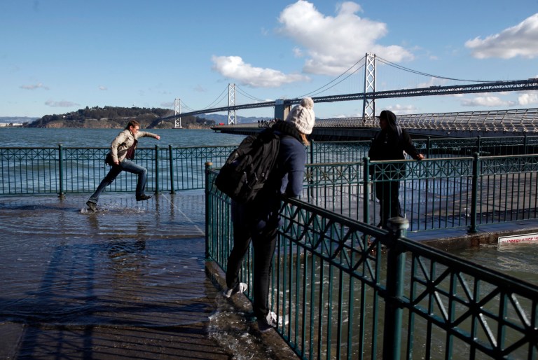   Pedestrians cannot resist getting close to Thursday's king's tide cresting along the San Francisco Embarcadero on Thursday, Dec. 13, 2012. The tide measured 7.2 at the Golden Gate and was the highest of the year. The king tides are expected to peak during the next several days, with surges over 9 feet in some areas. The phenomenon is caused by a unique alignment of the sun, moon and earth. (AP Photo/Bay Area News Group, Karl Mondon) MAGS OUT; NO SALES  
