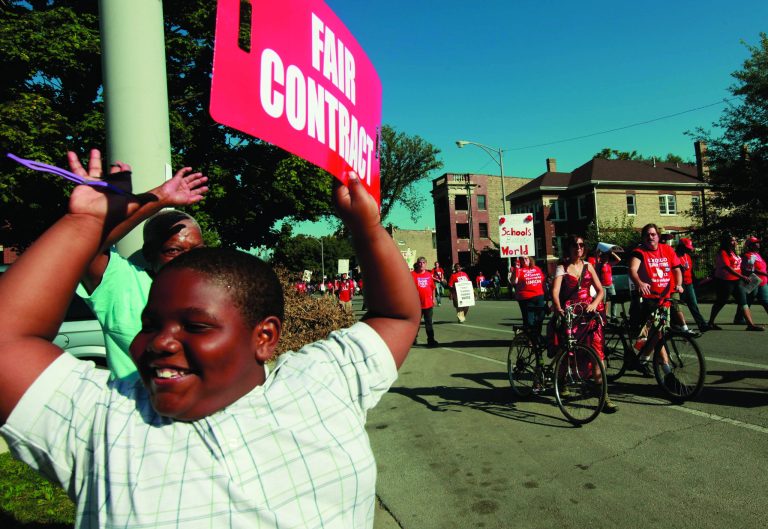 A young boy holds a placard in support of striking Chicago school teachers as they march after a rally Saturday, Sept. 15, 2012 in west Chicago. (AP Photo/Sitthixay Ditthavong)