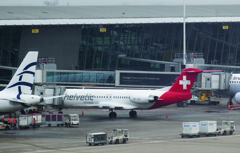 Baggage carts make their way past a Helvetic Airways aircraft from which about $50 million worth of diamonds were stolen on the tarmac of Brussels international airport Tuesday, Feb. 19, 2013. Eight armed and masked men made a hole in a security fence at the airport, drove onto the tarmac and snatched the diamonds from the hold of the Swiss-bound plane without firing a shot, authorities said Tuesday. (AP Photo/Yves Logghe)