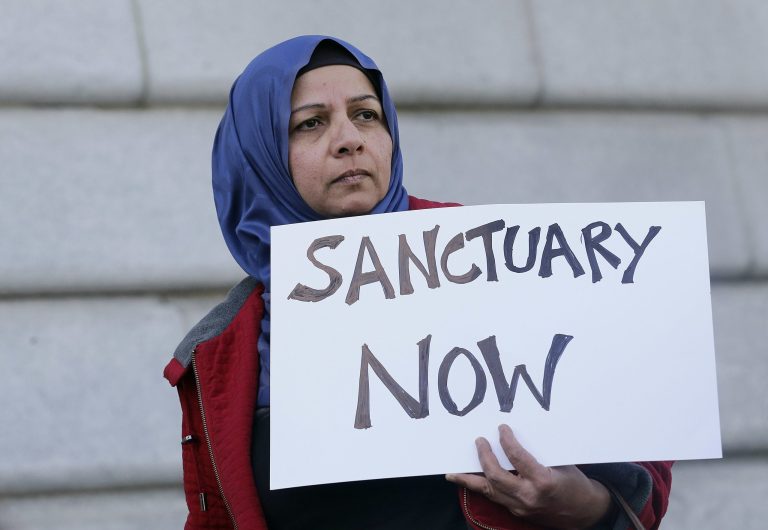 Moina Shaiq holds a sign at a rally outside of City Hall in San Francisco, Wednesday, Jan. 25, 2017. President Donald Trump moved aggressively to tighten the nation's immigration controls Wednesday, signing executive actions to jumpstart construction of his promised U.S.-Mexico border wall and cut federal grants for immigrant-protecting 