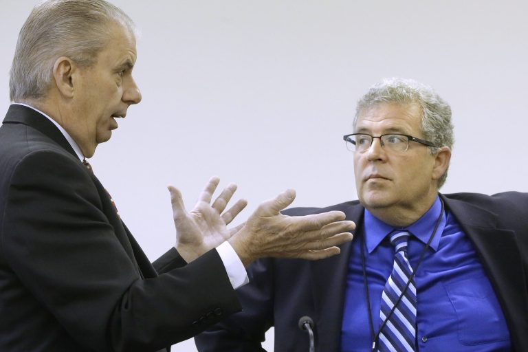 In this photo taken on Tuesday, May 6, 2014, Illinois Auditor General William Holland, left, and Illinois Rep. Frank Mautino, D-Spring Valley, right, talk during a legislative commission at the Illinois State Capitol in Springfield, Ill., that helps review the use of public money and voted to grant itself subpoena powers to investigate Illinois Gov. Pat Quinn's troubled anti-violence program. Mautino signed five of seven subpoenas compelling former state officials connected to Quinn's 2010 troubled anti-violence program to testify before a commission next month. (AP Photo/Seth Perlman)