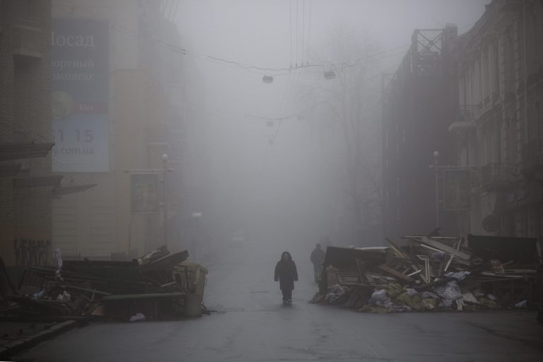 A woman passes by a barricade in a street heading to Kiev's Independence Square, Ukraine, Tuesday, March 4, 2014. Relieved investors sent stocks sharply higher Tuesday after Russia pulled troops back from the border of Ukraine. The rally erased steep losses from Monday caused by fears an escalating conflict. (AP Photo/Emilio Morenatti)