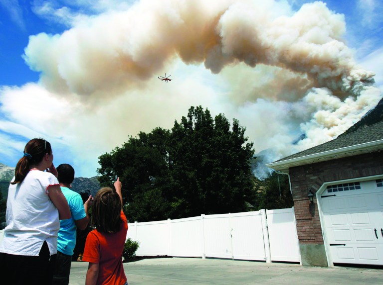 Emily and Byron Smith, and their son Ammon, 9, who returned after being evacuated, watch air crews continue to battle a wildfire near Alpine, Utah, on Wednesday, July 4, 2012. The fire has charred 2,887 acres and destroyed one barn since it started Tuesday afternoon. About 500 homes will remain evacuated for at least the next two days. (AP Photo/The Salt Lake Tribune, Francisco Kjolseth)