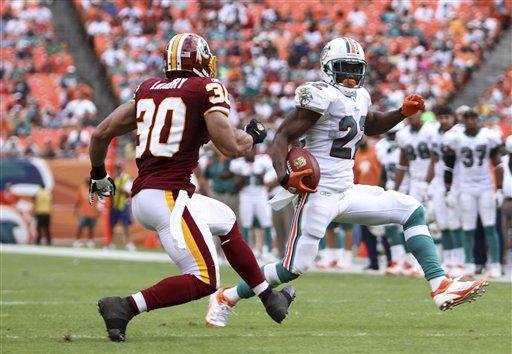 Miami Dolphins running back Reggie Bush (22) runs past Washington Redskins strong safety LaRon Landry (30) during the second quarter of an NFL football game Sunday, Nov. 13, 2011, in Miami. 
