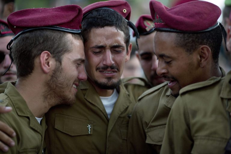 Israeli soldiers of the Paratroopers Brigade mourn over the grave of Sgt. Bnaya Rubel during his funeral at the military cemetery in Holon, Israel, Sunday, July 20, 2014. Rubel was killed while fighting Palestinian militants in Gaza on Saturday. (AP Photo/Ariel Schalit)