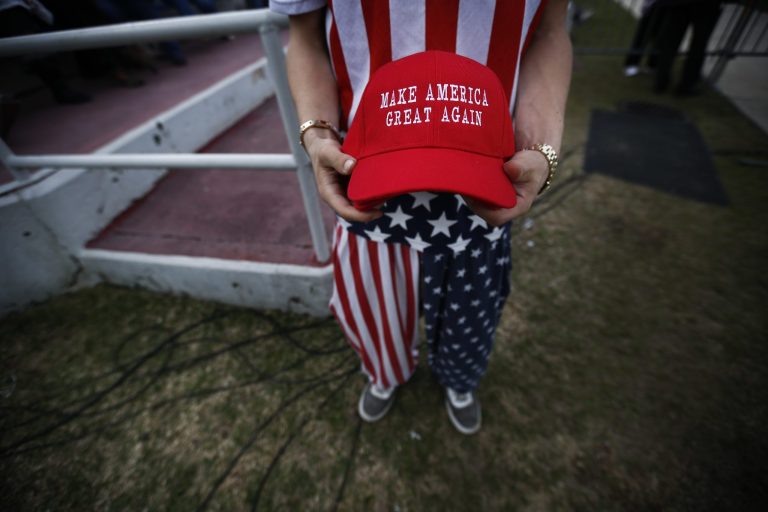 A man dressed in American flag clothes holds "Make America Great Again" hats in Mobile, Ala. (AP Photo/Brynn Anderson)