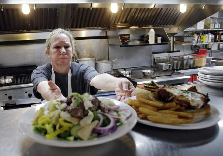 In this June 6, 2014 photo, cook Kim Jarjabka send out two lunch orders at Coppertop restaurant in Valley City, Ohio. According to research by the National Employment Law Project, restaurants and bars, temporary staffing, and retail account for more than one-third of the job gains in the current recovery.  Wages in these sectors average less than $13.34 an hour. (AP Photo/Mark Duncan)