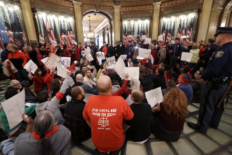 In this Dec. 11, 2012 file photo, protesters sit in the rotunda of the State Capitol in Lansing, Mich., in an unsuccessful effort to block passage of right-to-work legislation that bans labor agreements that require employees to pay fees to the unions that represent them. (AP Photo/Paul Sancya, File)