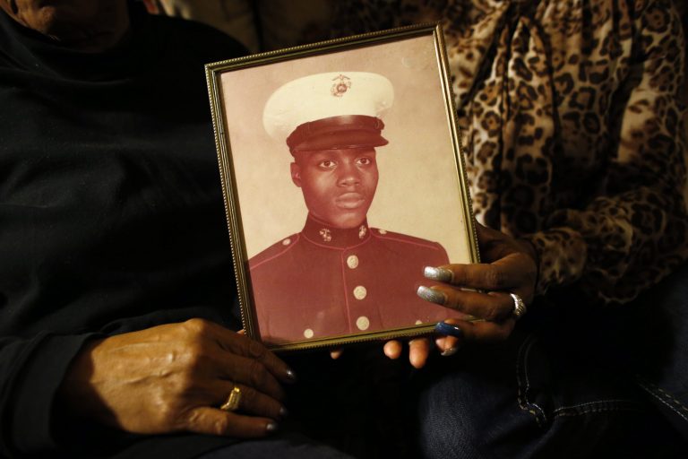 FILE - In this March 12, 2014 file photo, a picture of Jerome Murdough is held by his mother Alma Murdough left, and sister Cheryl Warner at Alma  Murdough's home in the Queens borough of New York. The homeless former Marine died in February in a Rikers Island jail cell that multiple city officials say was at least 100 degrees when his body was discovered.(AP Photo/Jason DeCrow, File)