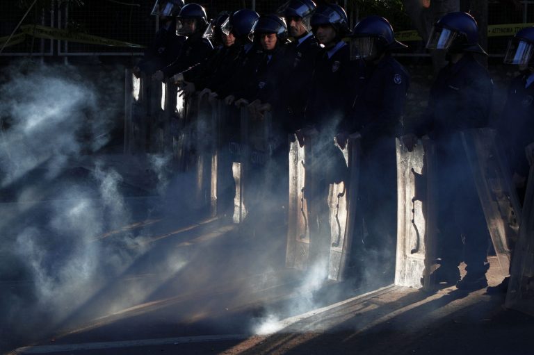 Smoke from a firework covers riot police after being thrown by a protestor outside of Parliament during a strike to protest government plans to privatize state-run organizations, Nicosia, Cyprus, Thursday, Feb. 27, 2014.  Hundreds of protesters have gathered outside Cyprus' parliament to voice opposition against legislation that will pave the way for the privatization of state-owned companies. (AP Photo/Petros Karadjias)