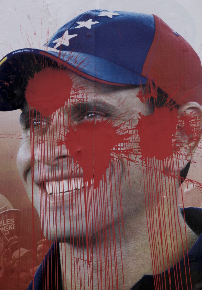 An old presidential election campaign poster, supporting a vote for opposition candidate Henrique Capriles, is defaced with red paint in Caracas, Venezuela, Monday, March 11, 2013. Capriles, who lost a presidential election against Venezuela's late President Hugo Chavez in October 2012, announced he will run again on April 14th in an election to replace Chavez who died on March 5 after a nearly two-year bout with cancer. (AP Photo/Rodrigo Abd)