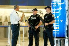 Passengers walk through JFK airport security, metal detectors buzzing