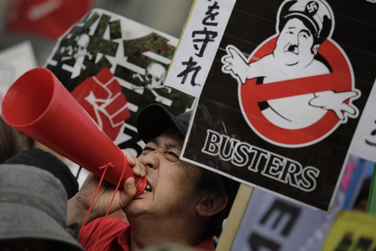 A protester shouts slogan outside the Japanese prime minister's office as the Cabinet approved reinterpreting the constitution on military affairs in Tokyo, Tuesday, July 1, 2014. Japan took a step away Tuesday from an American-drafted constitution that has long kept its military shackled, approving a plan to allow greater use of a force that was vanquished at the end of World War II. (AP Photo/Eugene Hoshiko)