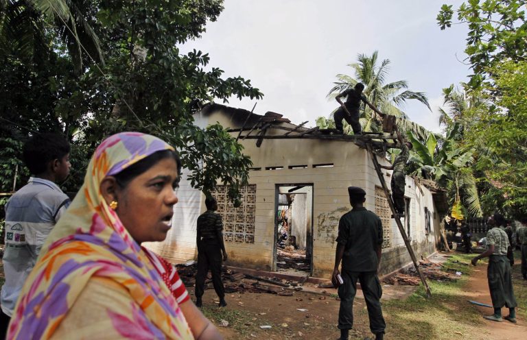 In this Friday, June 27, 2014 photo, a Sri Lankan Muslim woman watches as army soldiers salvage damaged household items from the debris of a burnt house in Darga Town in Aluthgama, about 50 kilometers (31 miles) south of Colombo, Sri Lanka. The onslaught by the Bodu Bala Sena (BBS), a hardline Buddhist group, killed two Muslims in the worst religious violence Sri Lanka has seen in decades. (AP Photo/Eranga Jayawardena)