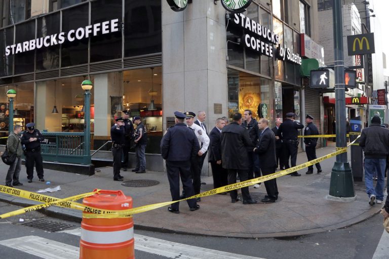 New York Police Department officers investigate a shooting near a subway station entrance at 35th Street and Eighth Avenue, Monday, in New York. Authorities said three people have been shot, one fatally. (AP Photo/Mark Lennihan)