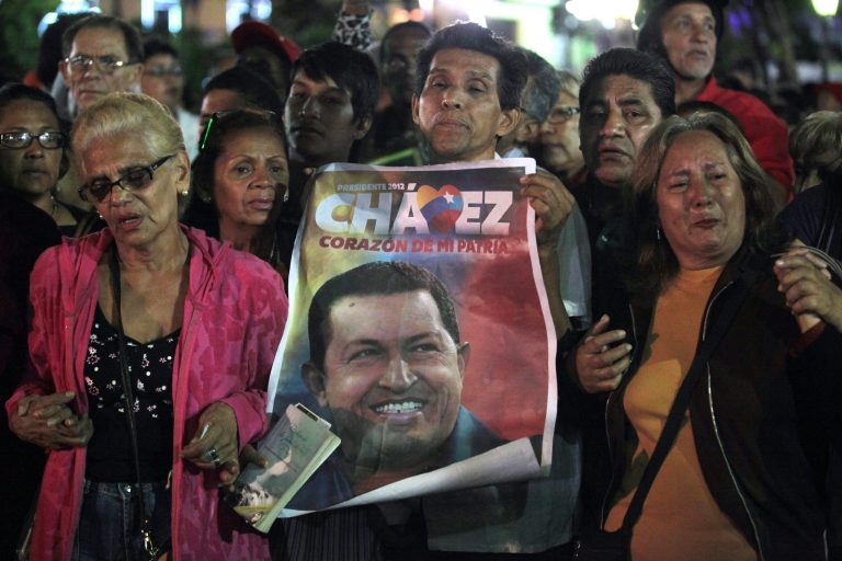   People, one holding an image of Venezuela's President Hugo Chavez, gather to pray for him at Simon Bolivar square in Caracas, Venezuela, Tuesday, Dec. 11, 2012. Doctors began operating on Chavez in Cuba, his government said, after his cancer reappeared despite a year and a half of surgeries and treatments. (AP Photo/Fernando Llano)  