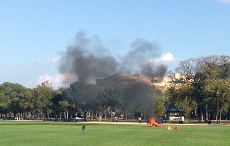 In this photo provided by Katy Scheflen, people run to a man who set himself on fire on the National Mall in Washington, Friday, Oct. 4, 2013. The reason for the self-immolation was not immediately clear and the man's identity was not disclosed. (AP Photo/Katy Scheflen)