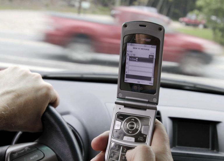   HOLD FOR RELEASE AT 12:01 A.M. EDT AND THEREAFTER ON THURSDAY, AUG. 22, 2013 - FILE - In this Sept. 20, 2011 file photo, a phone is held in a car in Brunswick, Maine. Americans are significantly less worried about drunk, aggressive and drowsy driving than they were four years ago even though traffic deaths have begun to edge back up, according to a survey by the AAA Foundation for Traffic Safety. At the same time, most Americans consider texting while driving completely unacceptable behavior, although one in four admit doing so recently. (AP Photo/Pat Wellenbach, File)  