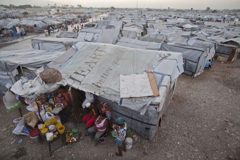 FILE - In this Jan. 9, 2013 file photo, residents of the Jean-Marie Vincent camp for people displaced by the 2010 earthquake, wait for customers outside their tent where they have set up a stand to sell rice, oil and canned goods, in Port-au-Prince, Haiti. More than a million people were left without homes in Haiti after the quake, but the remaining number of homeless now numbers about 146,000. (AP Photo/Dieu Nalio Chery, File)