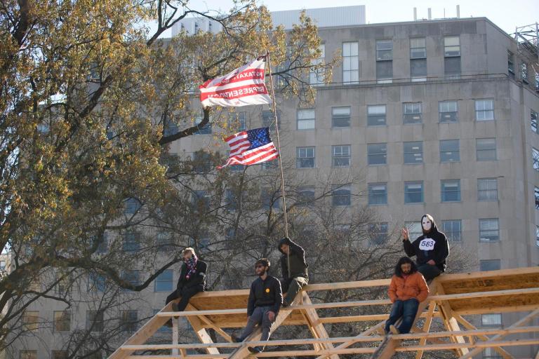 Members of the Occupy DC movement sit on a wooden structure at McPherson Square on Sunday in a clash that prompted the arrest of 31 people. 