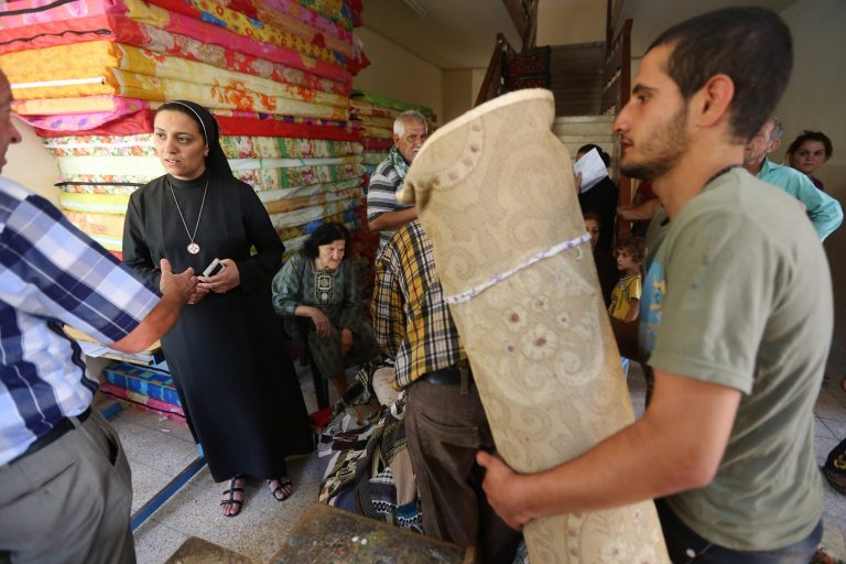 FILE - In this Friday, June 27, 2014, file photo, an Iraqi nun, second from left, speaks with a Christian man who fled with his family from the Christian villages near Mosul, Iraq, at a school that was turned into a shelter for displaced Christian families, in Ainkawa, a suburb of Irbil, Iraq. The Islamic State group gave Mosul's Christians until midday Saturday, July 19, 2014, to convert to Islam, pay a tax or face death. The vast majority of Christians fled. (AP Photo/Hussein Malla, File)