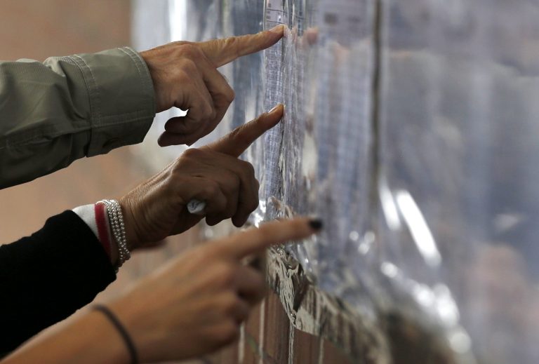 Voters check a list to confirm where they should cast their ballots during legislative elections in Bogota, Colombia, Sunday, March 9, 2014. (AP Photo/Fernando Vergara)