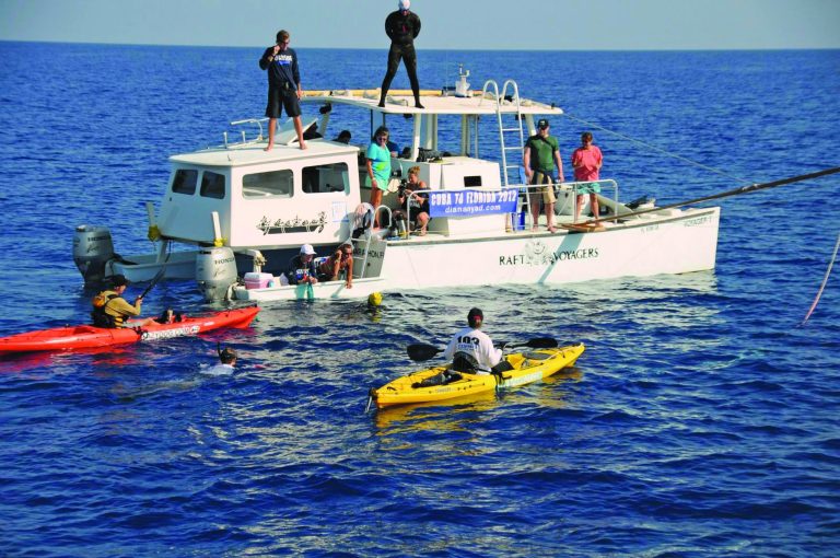 In this photo provided by Diana Nyad via the Florida Keys News Bureau, endurance swimmer Diana Nyad (yellow bathing cap) pauses for a rest and hydration with her support crew in the Florida Straits between Cuba and the Florida Keys, Sunday, Aug. 19, 2012. Nyad is endeavoring to become the first swimmer to transit the Florida Straits from Cuba to the Keys without a shark cage. (AP Photo/Diana Nyad via the Florida Keys News Bureau, Christi Barli)