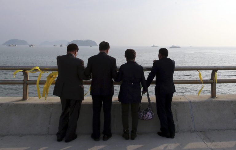 Christians pray near yellow ribbons with messages for the victims and missing passengers of the sunken ferry Sewol, at a port in Jindo, south of Seoul, South Korea, Monday, May 12, 2014. Bad weather prevented divers from searching inside the sunken, deteriorating South Korean ferry for a third day Monday. (AP Photo/Yonhap) KOREA OUT