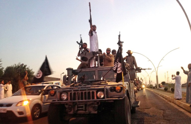 Fighters from the Islamic State group parade in a commandeered Iraqi security forces armored vehicle down a main road at the northern city of Mosul, Iraq. (AP Photo)