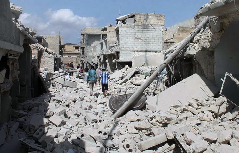 In this Saturday, Sept. 27 2014 photo, provided by the anti-government activist group Syrian Observatory for Human Rights, which has been authenticated based on its contents and other AP reporting, shows Syrians walking amid the rubble of damaged houses following a Syrian government airstrike in Aleppo, Syria. (AP Photo/Syrian Observatory for Human Rights)