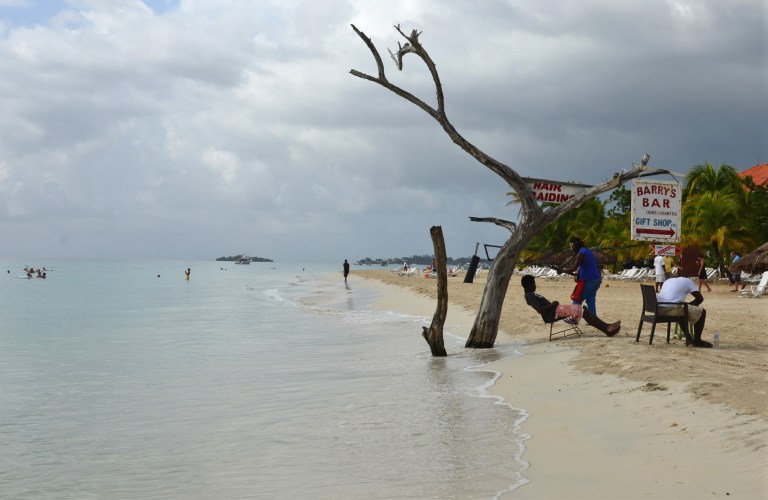 In this Sept. 14, 2014 photo, the tide gnaws away at a badly eroding patch of resort-lined beach in Negril in western Jamaica. The shrinking coastline long has raised worry for the region's environmental and economic future. Now, the erosion is expected to worsen as a result of climate change, and a hint of panic is creeping through this laid back village, one of the top destinations in a country where a quarter of all jobs depend on tourism. (AP Photo/David McFadden)