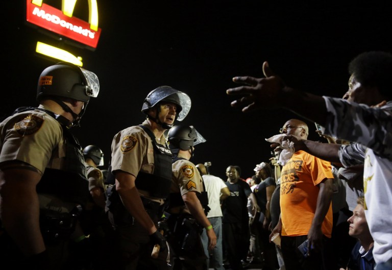 Officers and protesters face off along West Florissant Avenue, Monday, Aug. 10, 2015, in Ferguson, Mo. Ferguson was a community on edge again Monday, a day after a protest marking the anniversary of Michael Brown's death was punctuated with gunshots. (AP Photo/Jeff Roberson)
