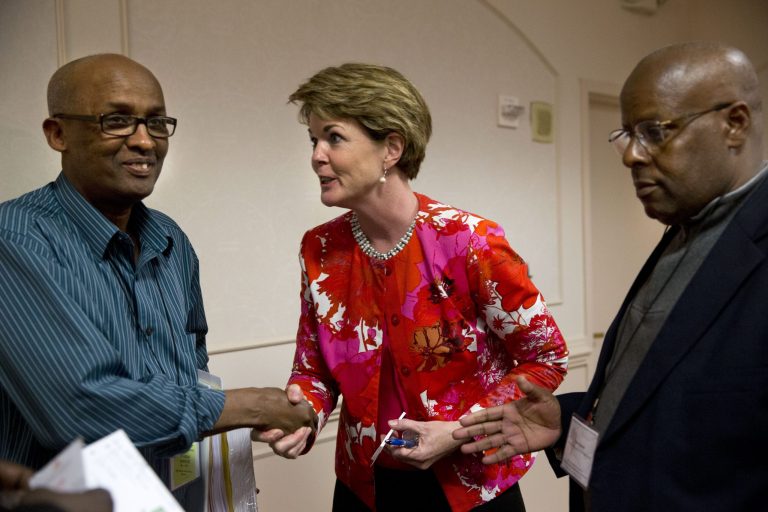 In this April 30, 2014 photo, Kathleen O'Connor, deputy chief of human rights and special prosecutions section at the Department of Justice, center, speaks to Mohamed Nur, left, with Della Lamb Community Services, of Kansas City, Mo., and Ibrahim Hussein with the East African Community of Orange County, Calif., who are both originally from Somalia, during an event for refugee advocates at the Holiday Inn in Arlington, Va. Justice Department representatives are speaking to immigrant communities to seek their help and coordination in identifying human rights abusers from abroad who have a connection to the United States. (AP Photo/Jacquelyn Martin)