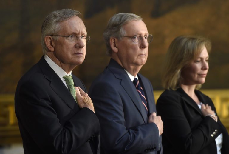 FILE - This July 9, 2014, file photo shows, from left, Senate Majority Leader Harry Reid of Nev., Senate Minority Leader Mitch McConnell of Ky., and Sen. Kirsten Gillibrand, D-N.Y., as they listen to the National Anthem during a ceremony on Capitol Hill in Washington. The Senate voted to advance an election-year bill limiting tax breaks for U.S. companies that move operations overseas. But big hurdles remain. (AP Photo/Susan Walsh, File)