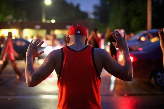 Demonstrators gather along West Florissant Avenue to protest the shooting of Michael Brown on Aug. 15, 2014 in Ferguson, Missouri. Brown was shot and killed by a Ferguson police officer on Aug. 9. Protestors raise their hands and chant 'Hands up, don't shoot' as a rally cry to draw attention to reports that stated Brown's hands were raised when he was shot. (Photo by Scott Olson/Getty images)