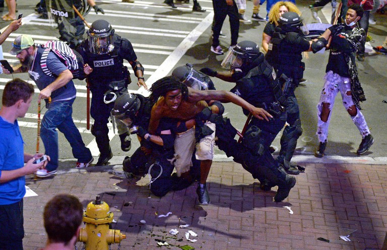 Authorities in Charlotte tried to quell public anger Wednesday after a police officer shot a black man, but a dusk prayer vigil turned into a second night of violence. (Jeff Siner/The Charlotte Observer via AP)