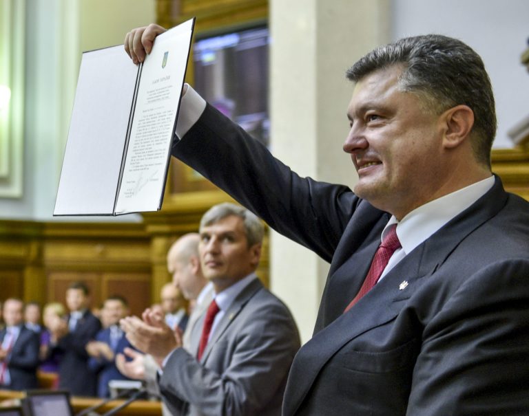 Ukrainian President Petro Poroshenko shows the Ukraine-EU Association Agreement to lawmakers  after its signing it in parliament in Kiev, Ukraine Tuesday, Sept. 16, 2014. Ukraine's parliament ratified an agreement to deepen economic and political ties with the European Union on Tuesday, and passed legislation to grant autonomy to the rebellious east as part of a peace deal. (AP Photo/Mykola Lazarenko)