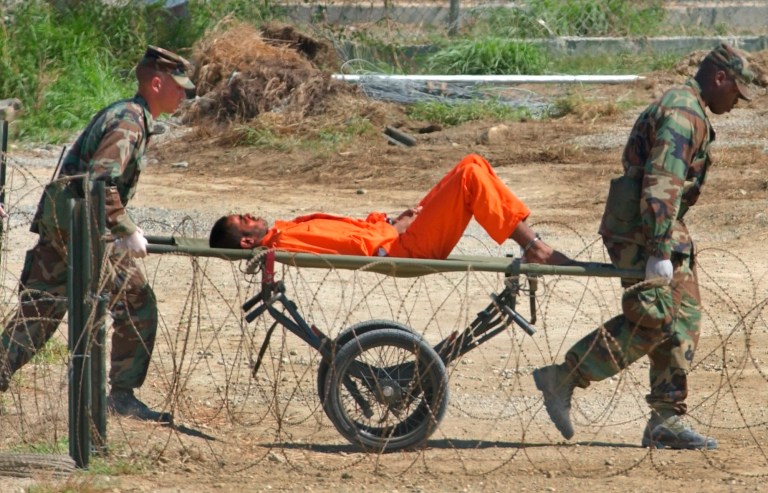 A detainee from Afghanistan is carried on a stretcher before being interrogated by military officials at Camp X-Ray at the U.S. Naval Base in Guantanamo Bay, Cuba, on Feb. 2, 2002. (AP Photo/Lynne Sladky)