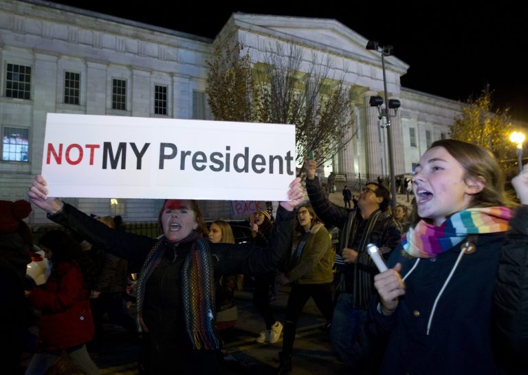 A demonstrator holds a banner as they protest during a march in downtown Washington in opposition of President-elect Donald Trump, on Saturday, Nov. 12, 2016. More than 200 people, carrying signs, gathered on the steps of the Washington state Capitol. The group chanted 
