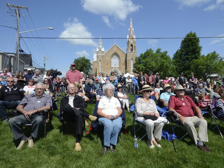 People watch a church service from outside in Lac-Megantic, Que. on Sunday July 6, 2014 on the first anniversary of a train derailment in the small Quebec town that killed 47 people. A parked Montreal, Maine & Atlantic Railway train with 72 tankers of crude oil rolled down an incline, derailed and slammed into downtown Lac-Megantic last July 6. Several tankers exploded, destroying 40 buildings in the lakeside town of 6,000. (AP Photo/The Canadian Press, Ryan Remiorz)